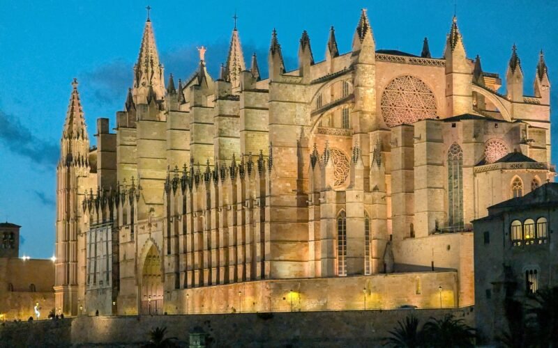 Große Kathedrale auf Mallorca, beleuchtet bei Dämmerung, mit beeindruckender Architektur und warmem Licht