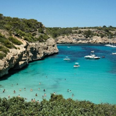 Gruppe von Menschen am Strand auf Mallorca bei Sonnenuntergang, Wasser im Hintergrund, entspannte Atmosphäre