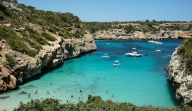Gruppe von Menschen am Strand auf Mallorca bei Sonnenschein, Wasser im Hintergrund, aufgenommen von Mariya Oliynyk