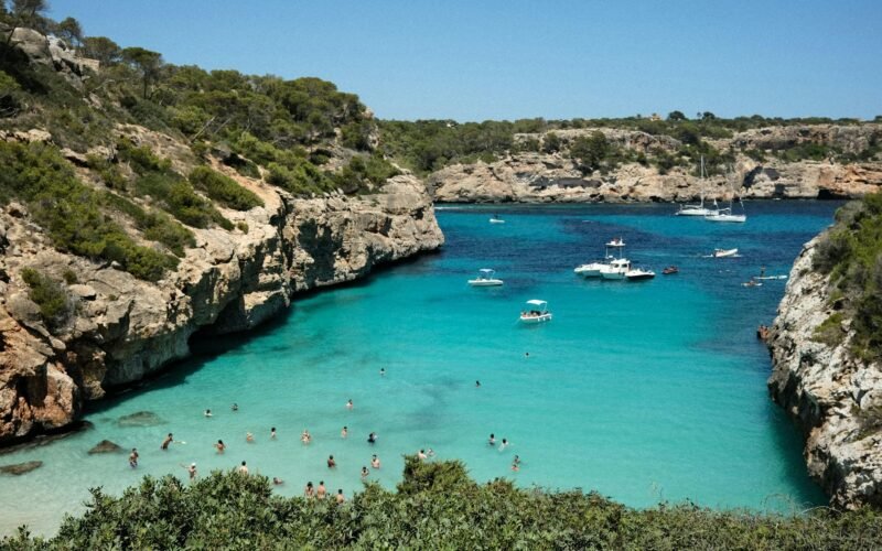 Gruppe von Menschen am Strand auf Mallorca bei Sonnenschein, Wasser im Hintergrund, aufgenommen von Mariya Oliynyk