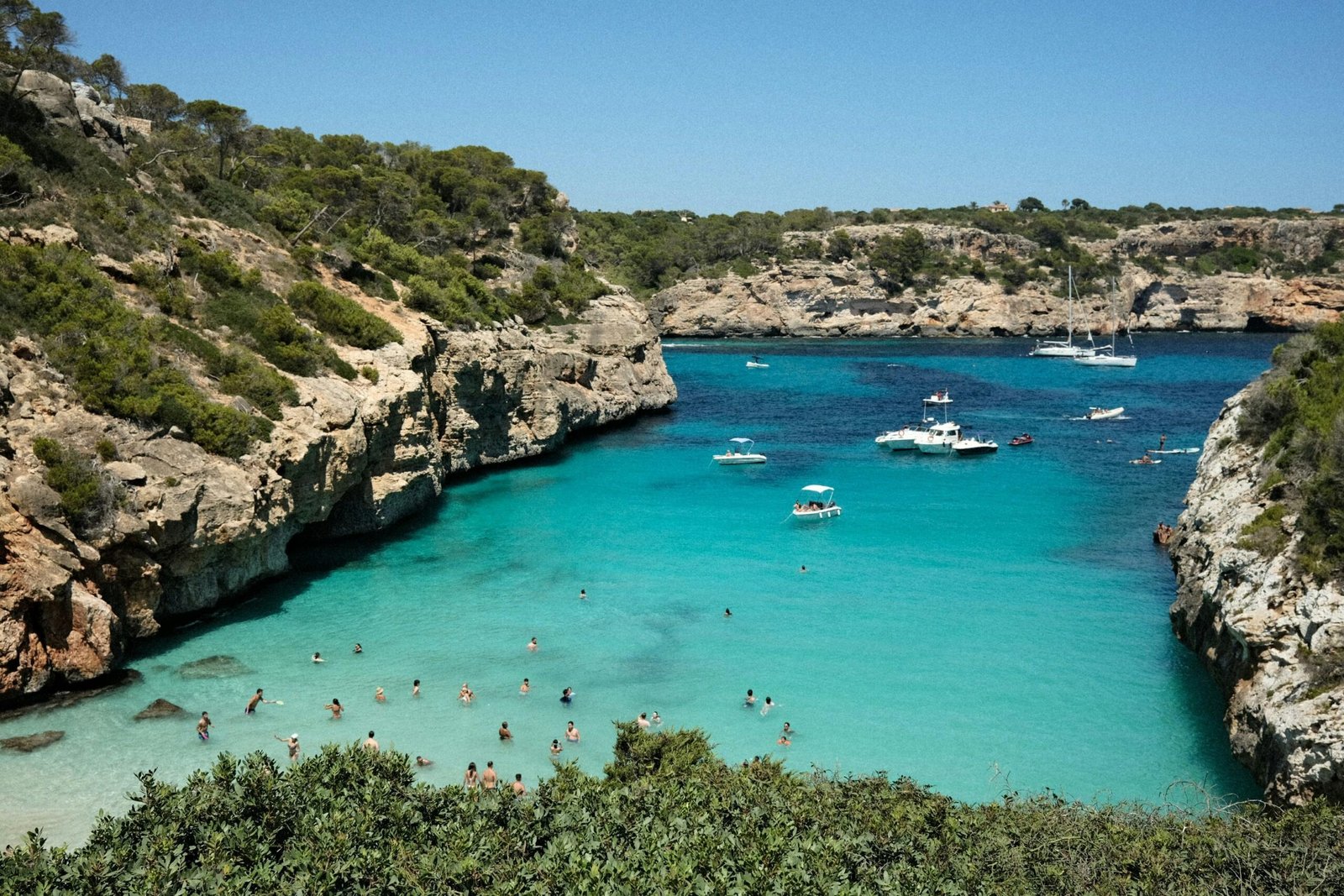 Gruppe von Menschen am Strand auf Mallorca bei Sonnenschein, Wasser im Hintergrund, aufgenommen von Mariya Oliynyk