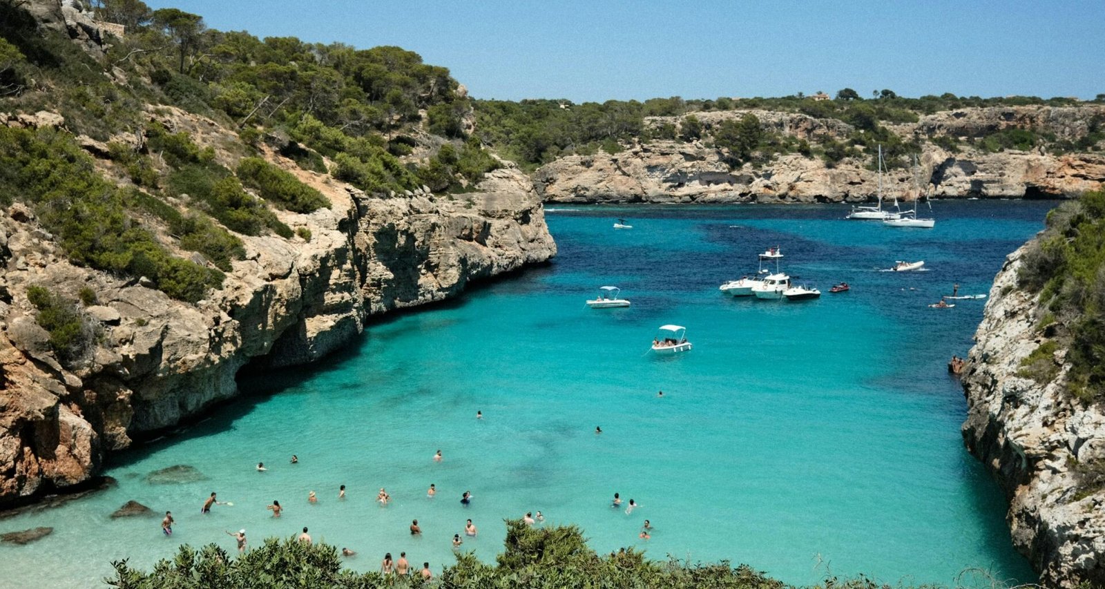 Gruppe von Menschen am Strand auf Mallorca bei Sonnenuntergang, Wasser im Hintergrund, aufgenommen von Mariya Oliynyk