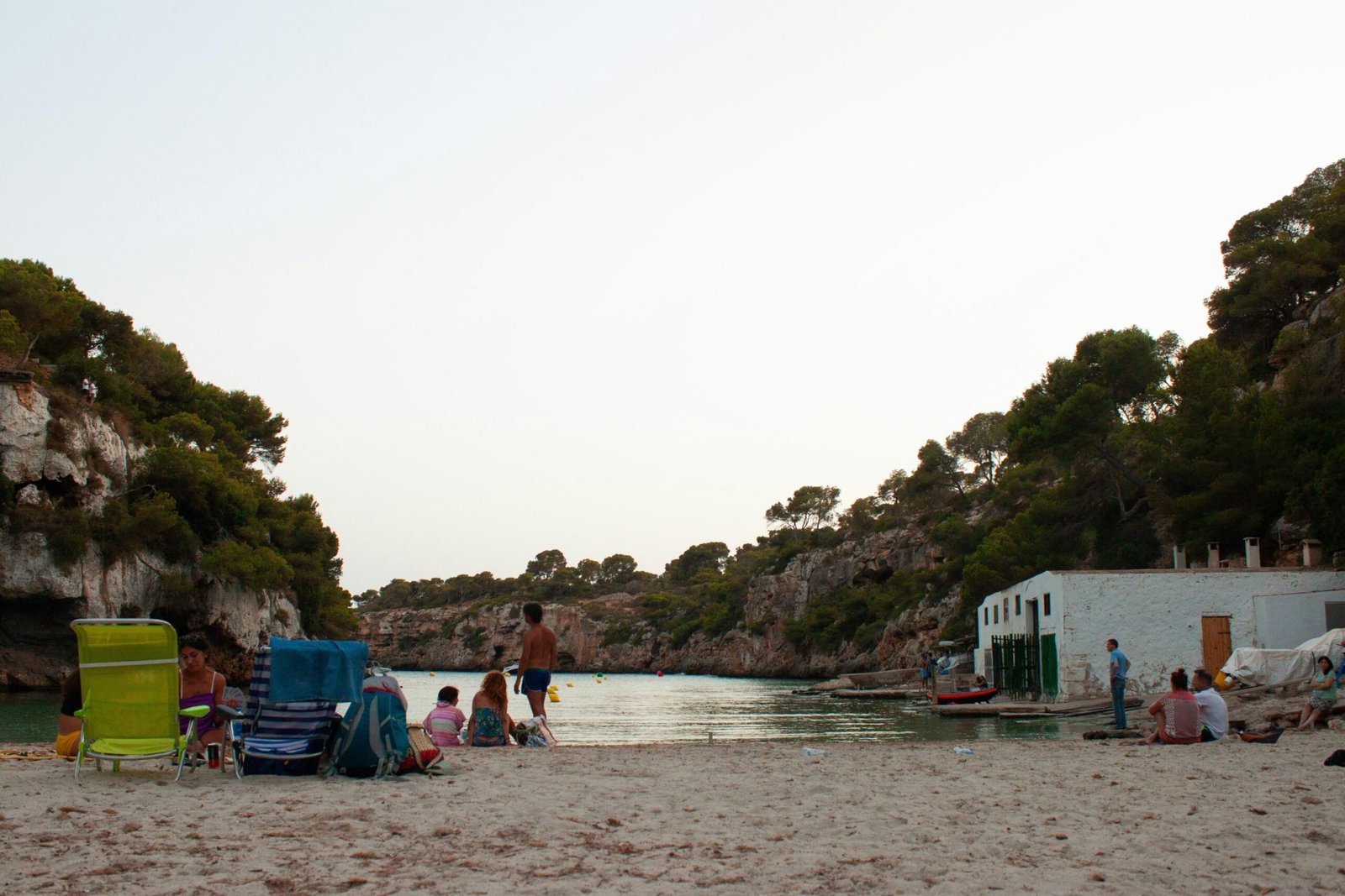 Gruppe von Menschen sitzt am Strand auf Mallorca neben einem Wasserlauf, aufgenommen von MIGUEL BAIXAULI.