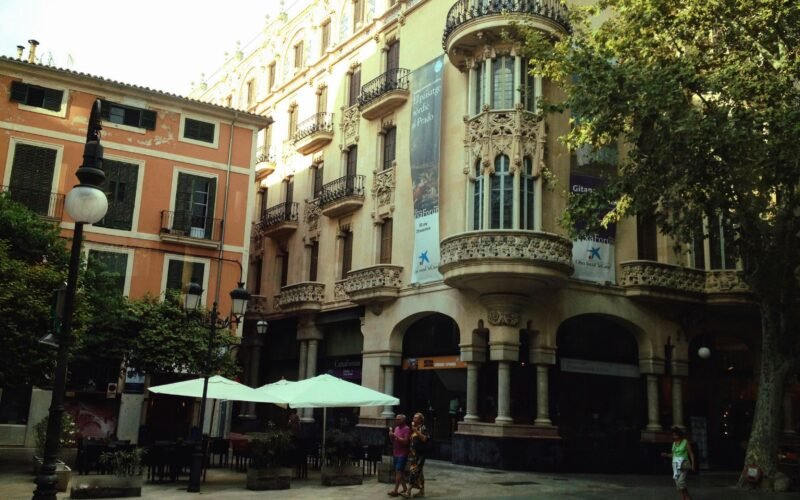 Gruppe von Menschen beim Spaziergang auf Mallorca neben einem alten Gebäude, aufgenommen von Carla M.J. Gomes.
