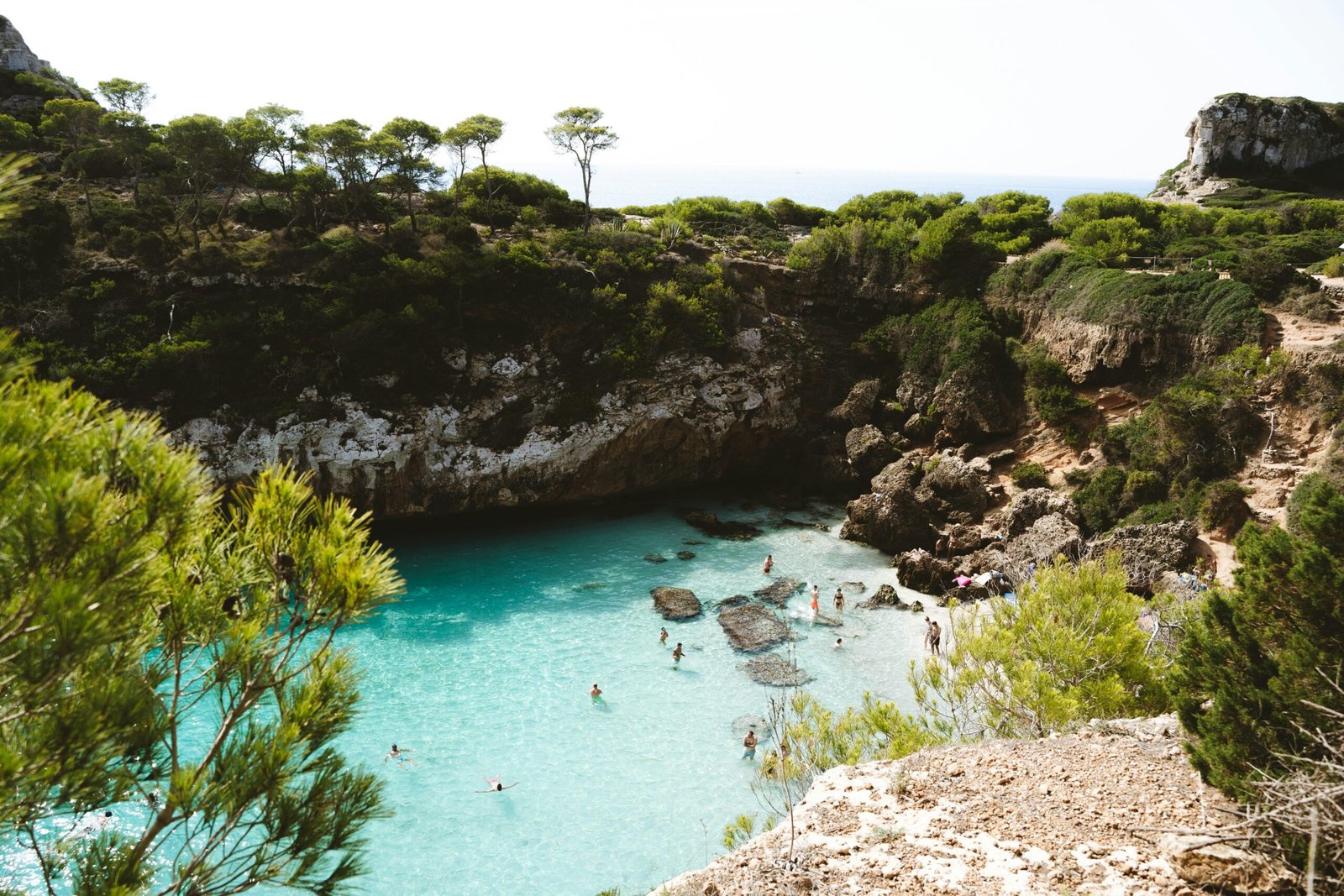 Gruppe von Menschen schwimmt in einer blauen Lagune auf Mallorca, umgeben von klarem Wasser und Natur.