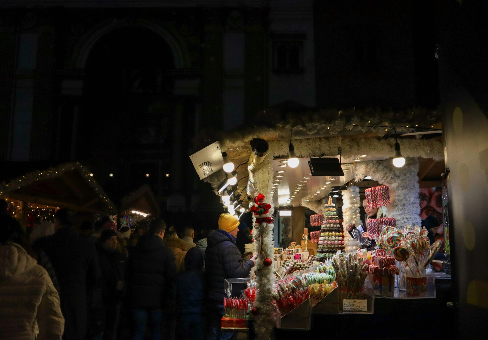 Gruppe von Menschen steht draußen vor einem Laden bei Nacht auf Mallorca, aufgenommen von Viola Kovács.