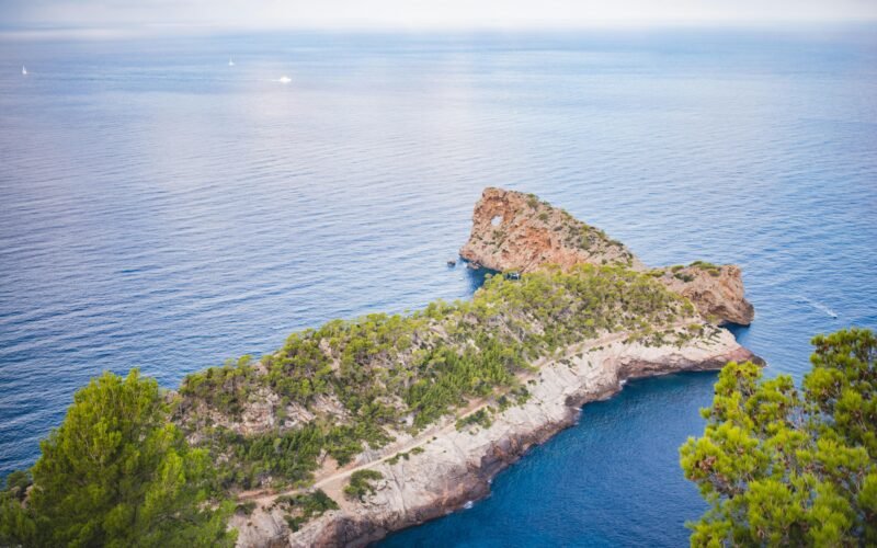 Kleine Insel inmitten des Ozeans auf Mallorca, fotografiert von Monika Guzikowska, zeigt die unberührte Natur und das klare Wasser.