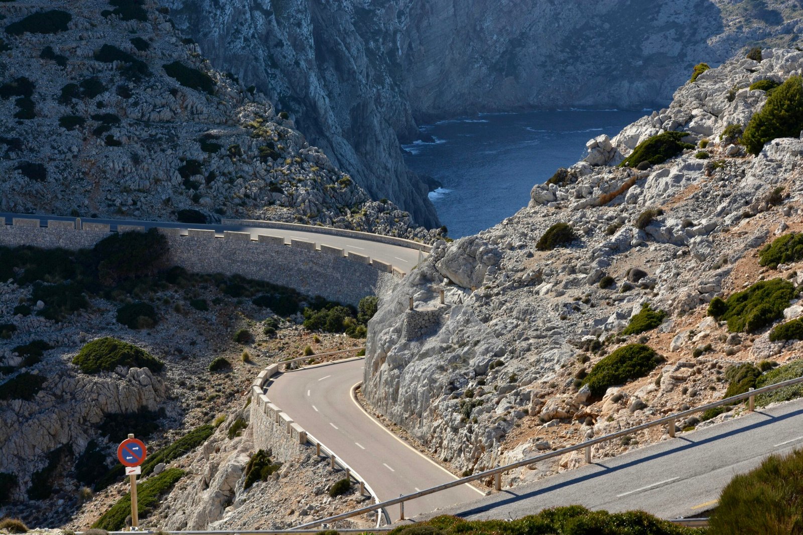 Eine gewundene Straße an den Berghängen auf Mallorca, umgeben von Natur und felsigen Landschaften.
