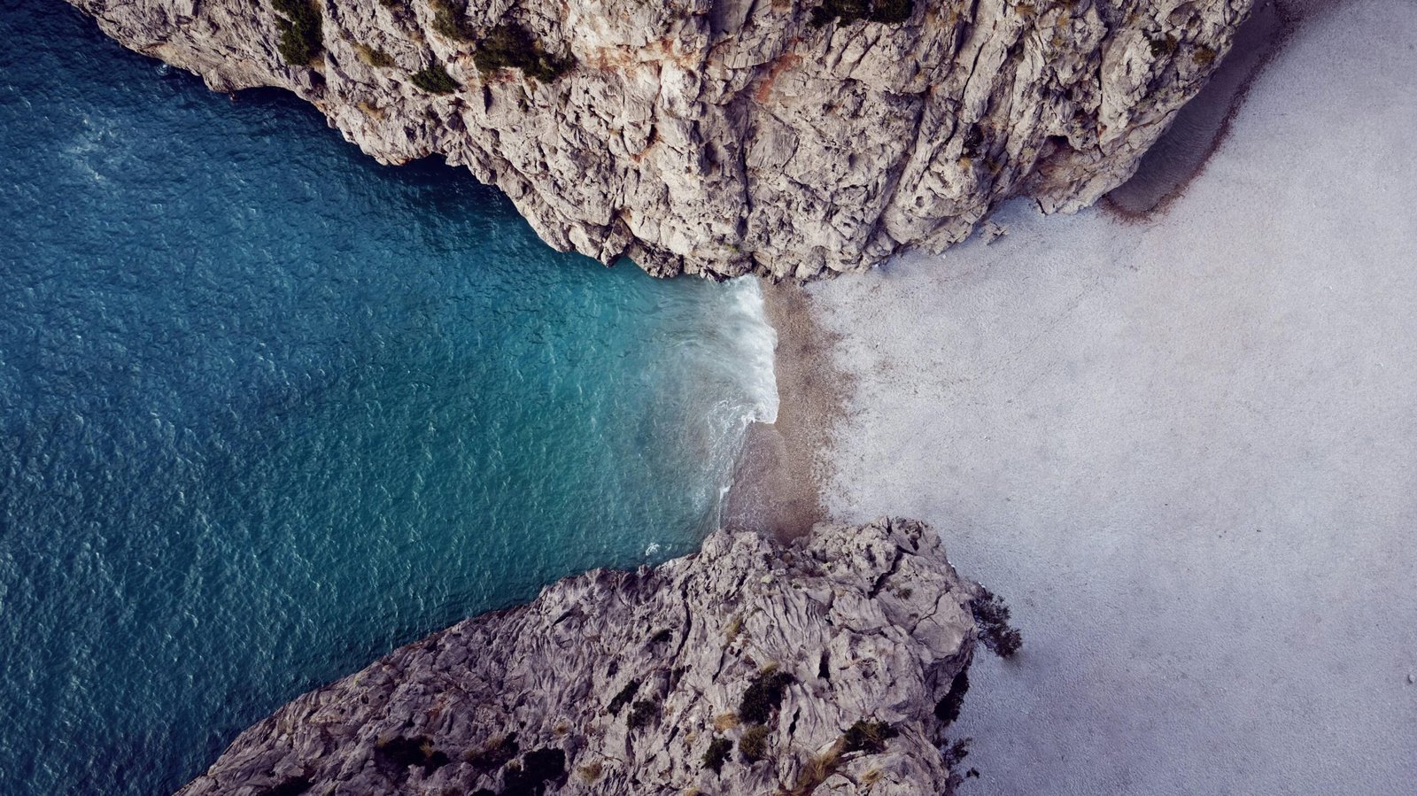 Luftaufnahme einer felsigen Bucht mit Wasser auf Mallorca, aufgenommen von Alex Kulikov
