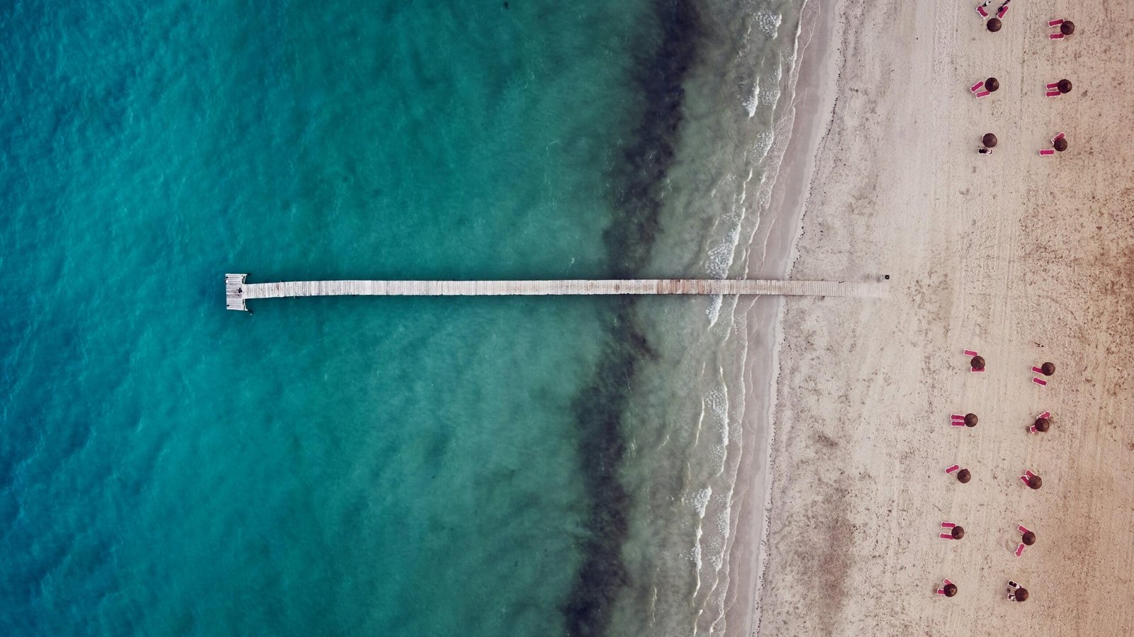 Luftaufnahme eines Strandes mit Pier auf Mallorca, fotografiert von Alex Kulikov