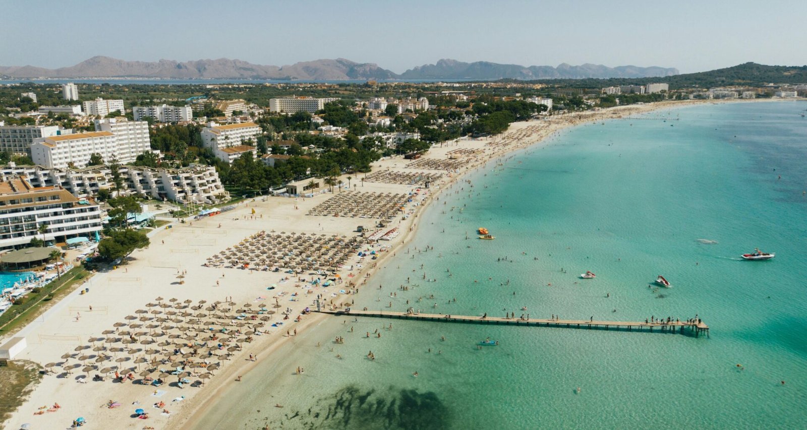 Pitoreske Strandkulisse auf Mallorca mit Touristen, Sand und Gebäuden, aufgenommen von Tomas Eidsvold.