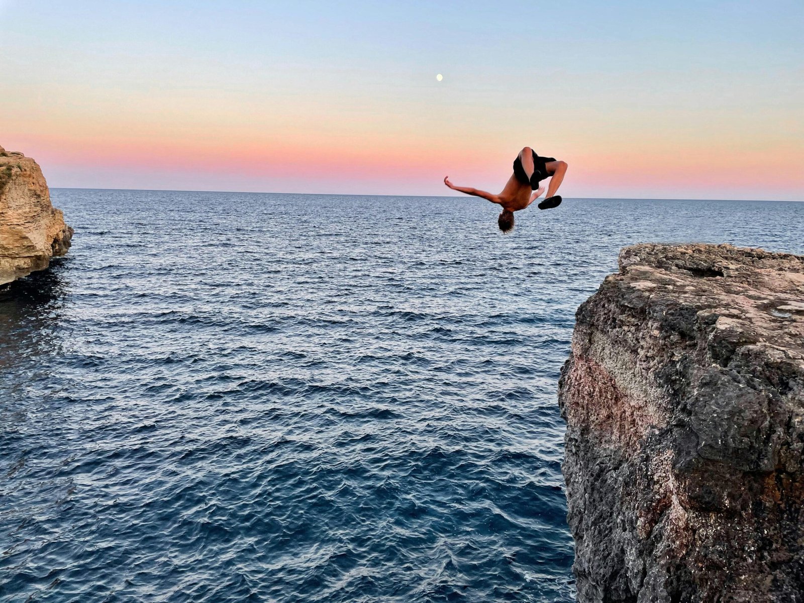 Person springt von einer Klippe ins Wasser auf Mallorca, aufgenommen von Luis