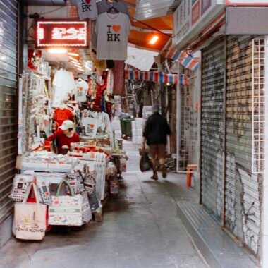 Person läuft durch eine enge Marktgasse mit Geschäften auf Mallorca, fotografiert von Zhen Yao