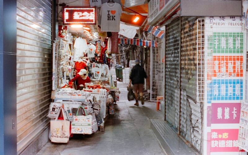 Person läuft durch eine enge Marktgasse mit Geschäften auf Mallorca, aufgenommen von Zhen Yao