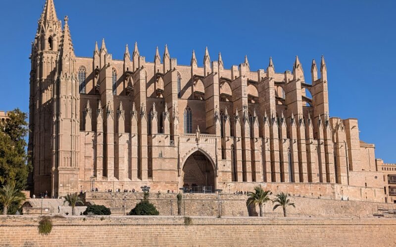 Große gotische Kathedrale mit kunstvollen Spitztürmen auf Mallorca bei strahlendem Himmel, fotografiert von David Vives.