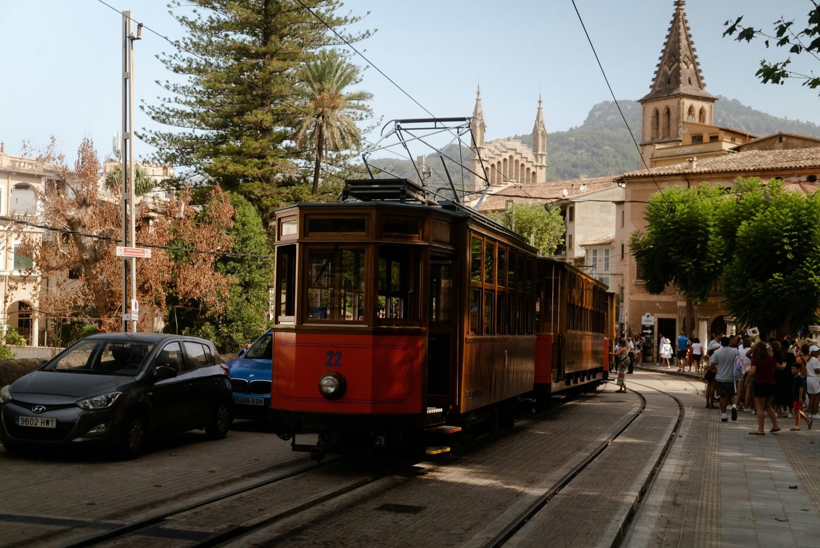 Roter Trolley fährt die Straße entlang auf Mallorca, umgeben von hohen Gebäuden, aufgenommen von Victor Oonk.