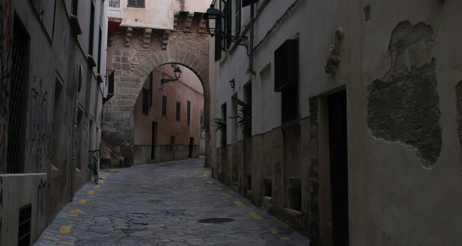 Narrow cobblestone street leading to an archway auf Mallorca, fotografiert von Susana Bartolome