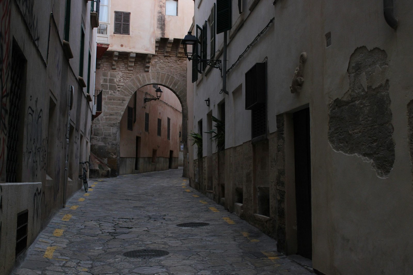 Narrow cobblestone street leading to an archway auf Mallorca, fotografiert von Susana Bartolome
