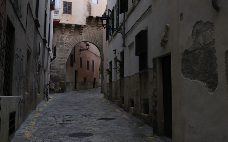 Narrow cobblestone street leading to an archway auf Mallorca, fotografiert von Susana Bartolome