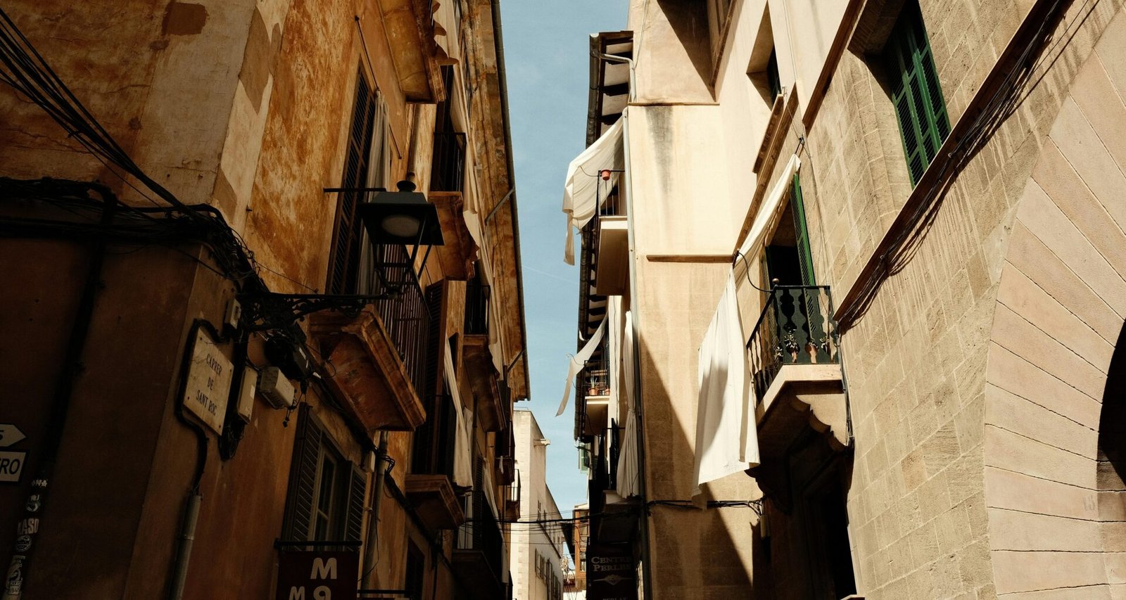 Narrow city street auf Mallorca mit alten Gebäuden und einer Uhr an der Wand, aufgenommen von Felix.