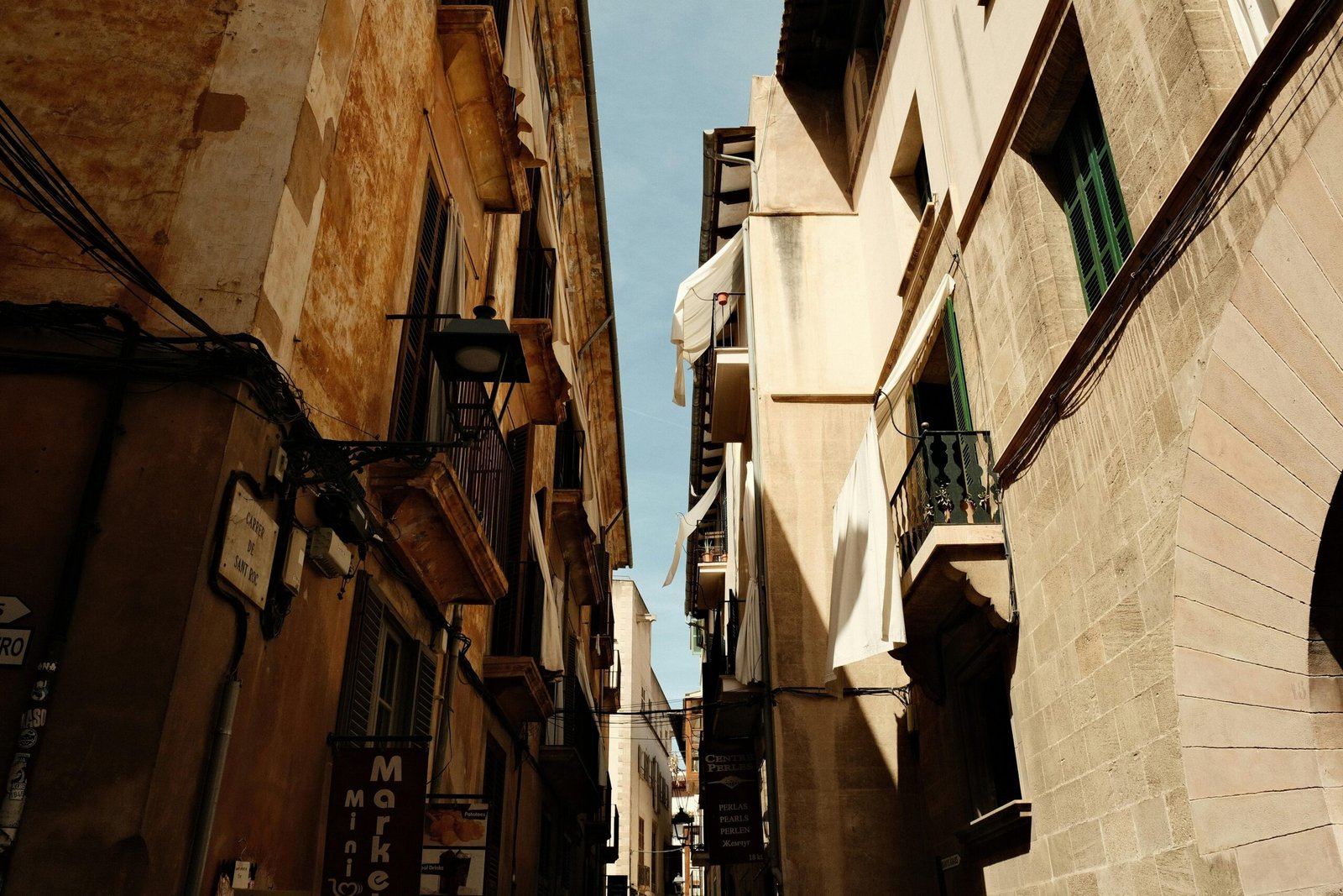 Narrow city street auf Mallorca mit alten Gebäuden und einer Uhr an der Wand, aufgenommen von Felix.