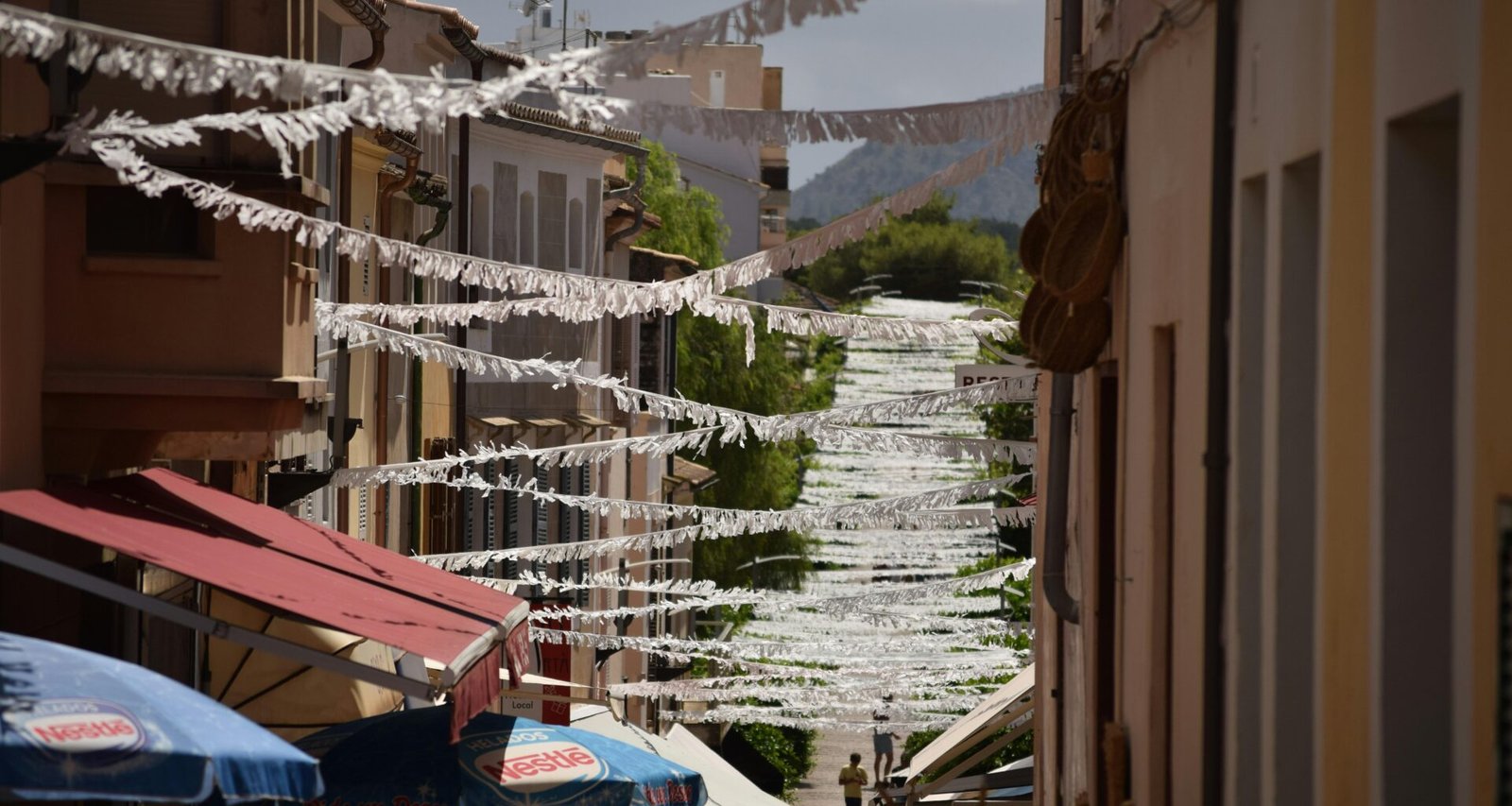 Narrow street lined with buildings and umbrellas auf Mallorca, aufgenommen von Jannik.