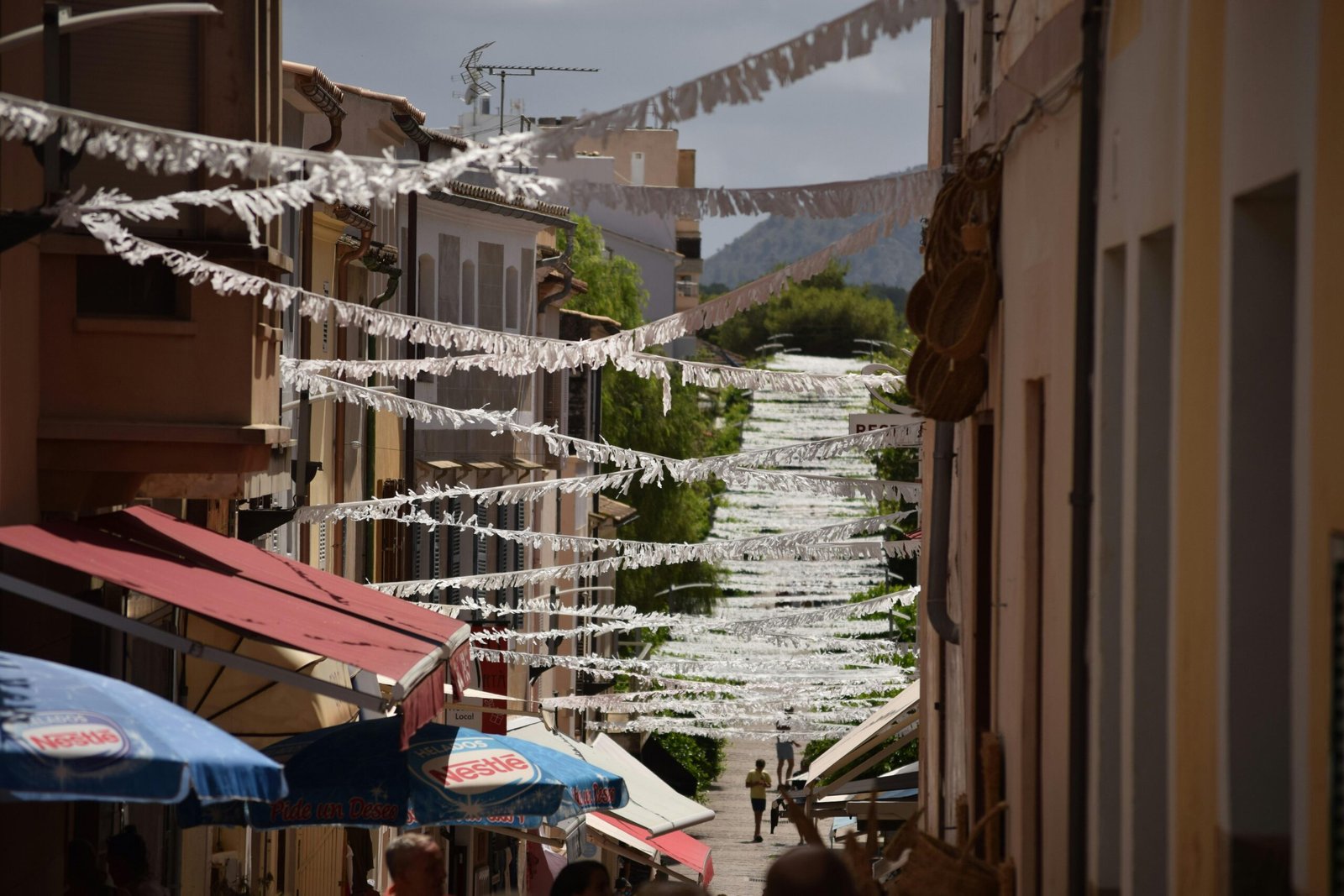 Narrow street lined with buildings and umbrellas auf Mallorca, fotografiert von Jannik.