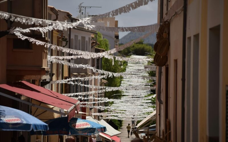 Narrow street lined with buildings and umbrellas auf Mallorca, fotografiert von Jannik