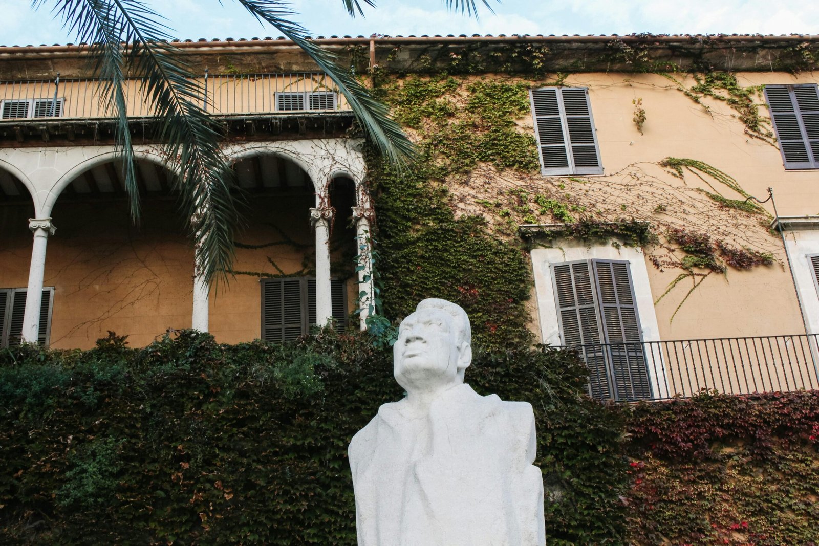 Statue eines Mannes vor einem historischen Gebäude auf Mallorca, aufgenommen von Behnaz.
