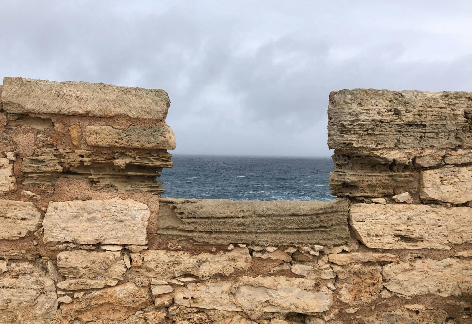 Steinmauer mit Blick auf den Ozean und bewölkten Himmel auf Mallorca, aufgenommen von yelr