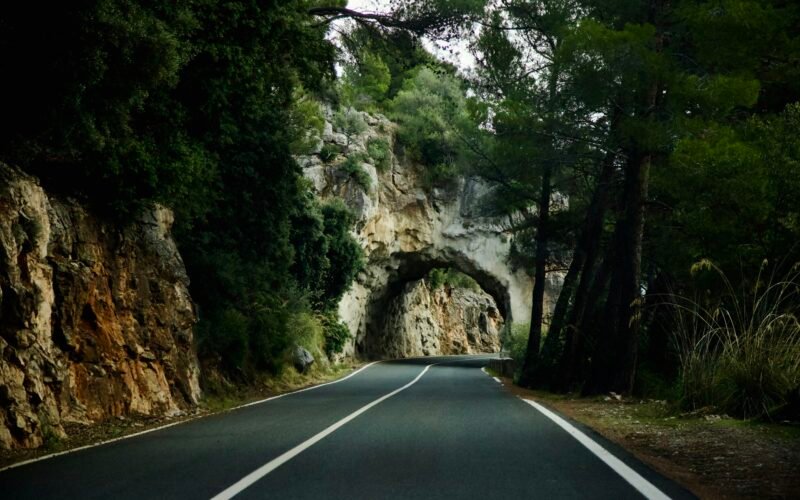 Eine Straße mit einem Tunnel in der Mitte auf Mallorca, umgeben von natürlicher Landschaft, fotografiert von Stock Birken