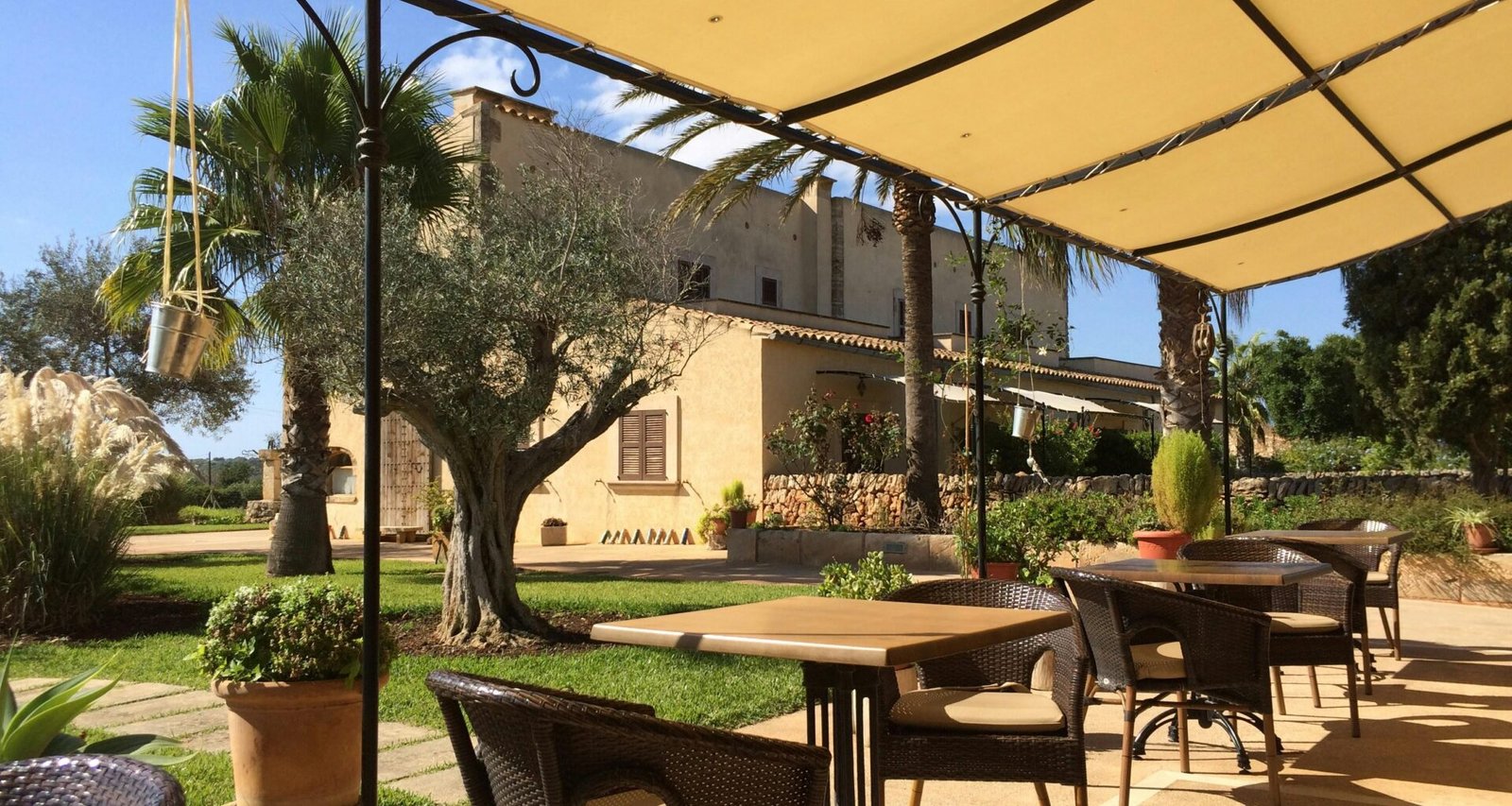 Patio auf Mallorca mit Tischen und Stühlen unter einem Sonnenschirm, perfekt für eine entspannte Atmosphäre