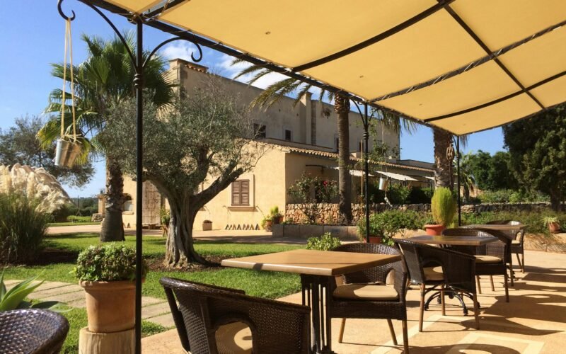 Patio auf Mallorca mit Tischen und Stühlen unter einem Sonnenschirm, perfekt für eine entspannte Atmosphäre