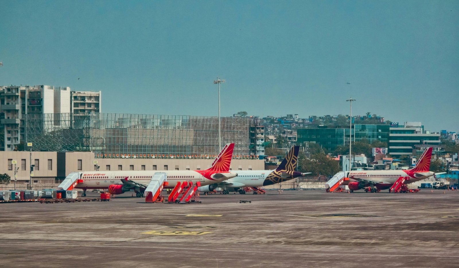 Flugzeuge stehen auf dem Tarmac eines Flughafens auf Mallorca mit Gebäuden im Hintergrund, aufgenommen von Zoshua Colah.