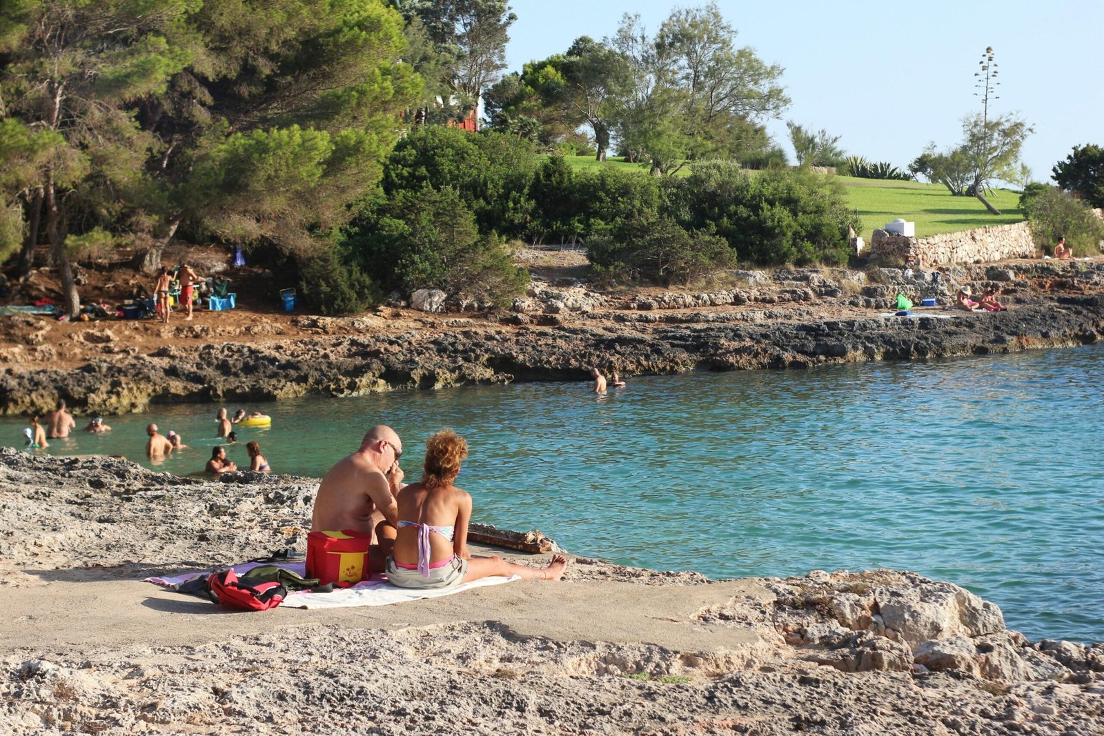 Frau in pinkem Bikini liegt entspannt auf Sand am Strand auf Mallorca bei Tageslicht, Blick auf das Wasser