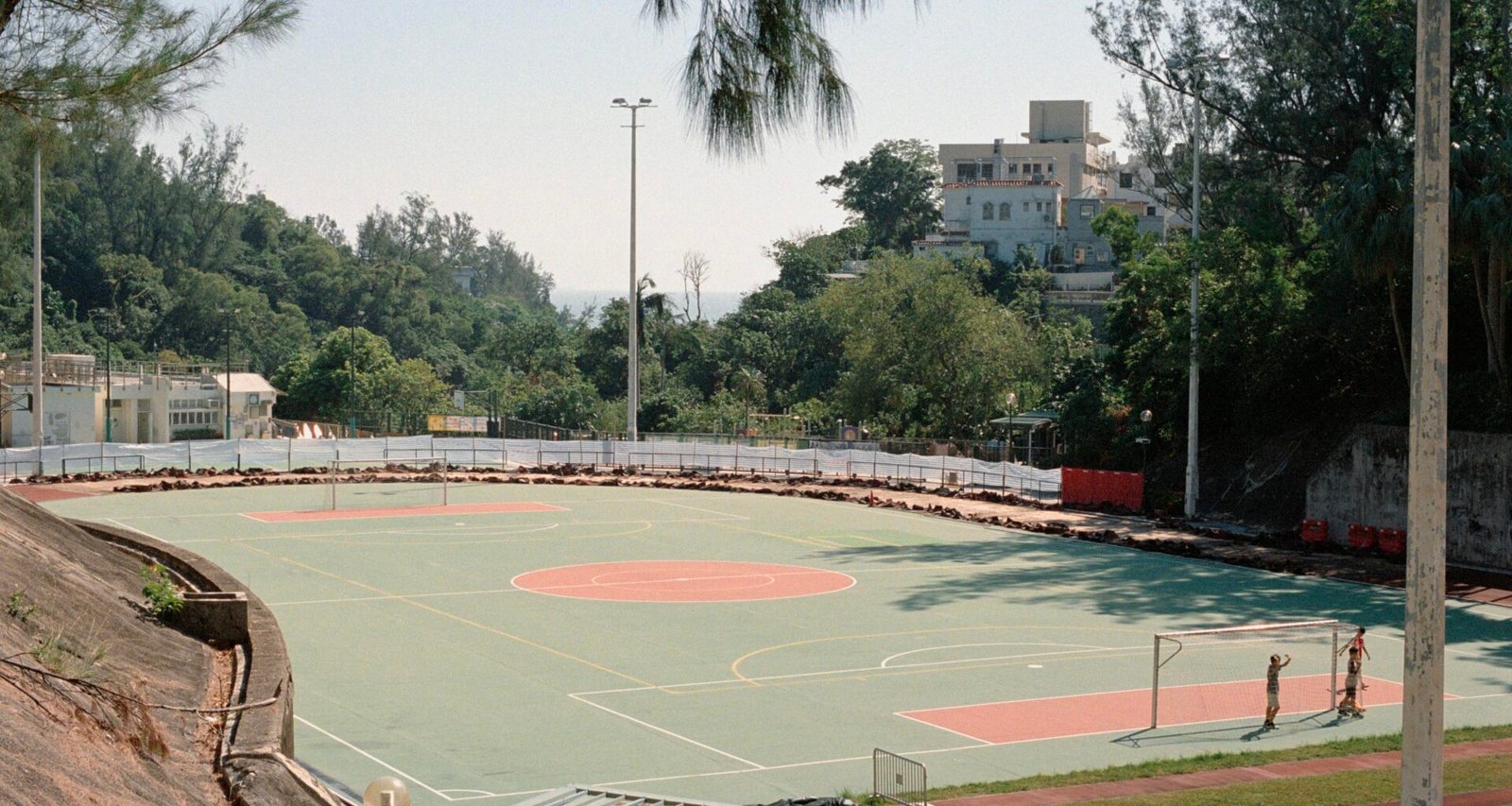 Außenbasketballplatz auf Mallorca mit Bäumen und Gebäuden im Hintergrund, fotografiert von Zhen Yao