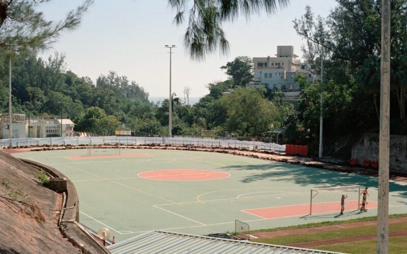 Außenbasketballplatz auf Mallorca mit Bäumen und Gebäuden im Hintergrund, fotografiert von Zhen Yao