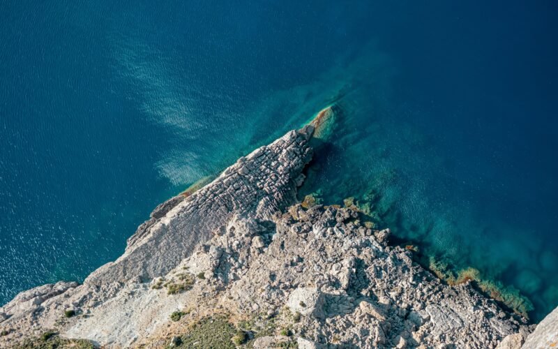 Klares Wasser nahe einer Insel auf Mallorca, aufgenommen von Christian Waske, mit Blick auf die ruhige Meeresoberfläche.