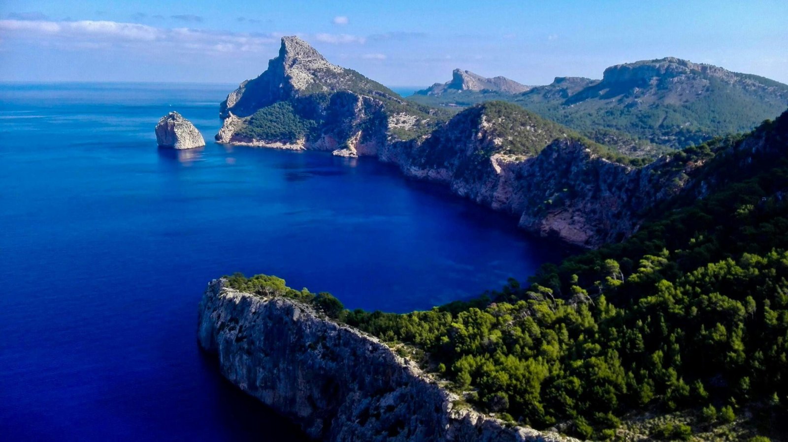 Grüner und brauner Berg neben blauem Meer unter blauem Himmel auf Mallorca, aufgenommen von Doloresz Dombi