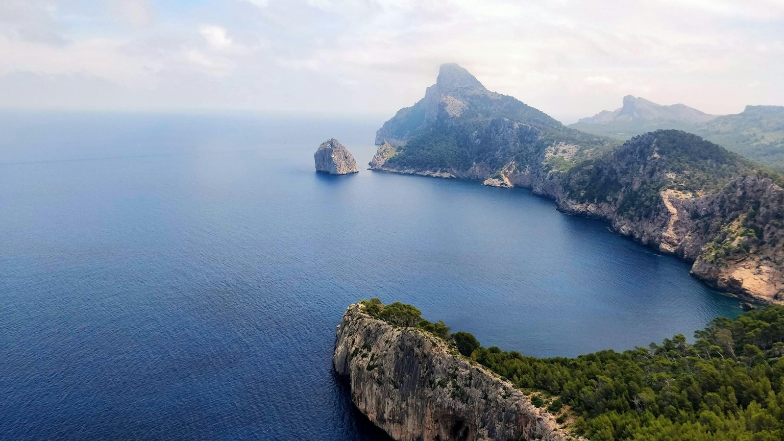 Berglandschaft mit grünem und braunem Berg neben blauem Meer unter weißem Himmel auf Mallorca, aufgenommen von Vishwas Katti.