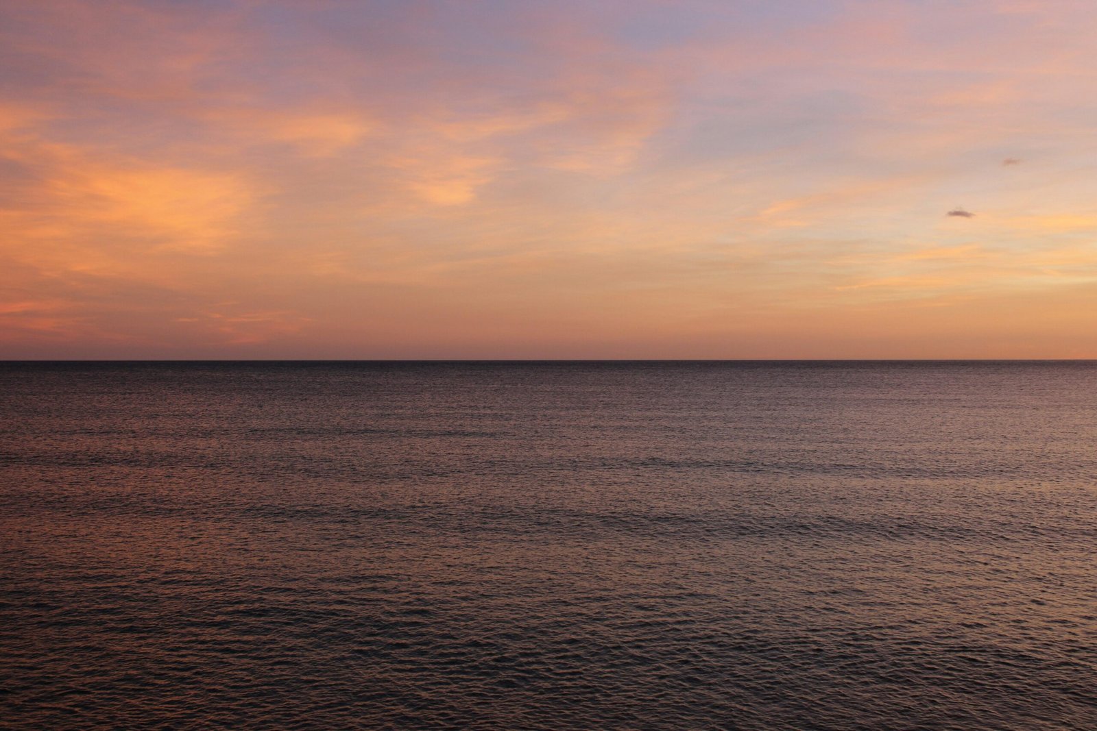 Das Meer auf Mallorca spiegelt den Sonnenuntergang wider, mit warmen Farben am Horizont