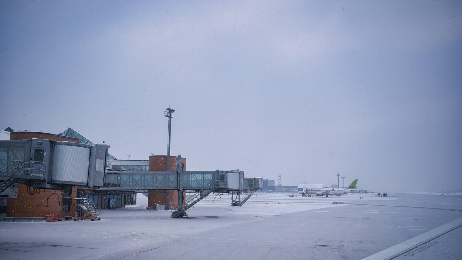 Jetbrücken und ein Flugzeug auf verschneitem Flughafen-Tarmac auf Mallorca, aufgenommen von Maksim Shutov