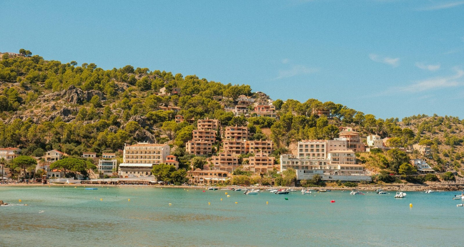 Küstenort auf Mallorca, eingebettet in einen bewaldeten Hügel mit Blick auf das Meer, aufgenommen von Alexis Presa