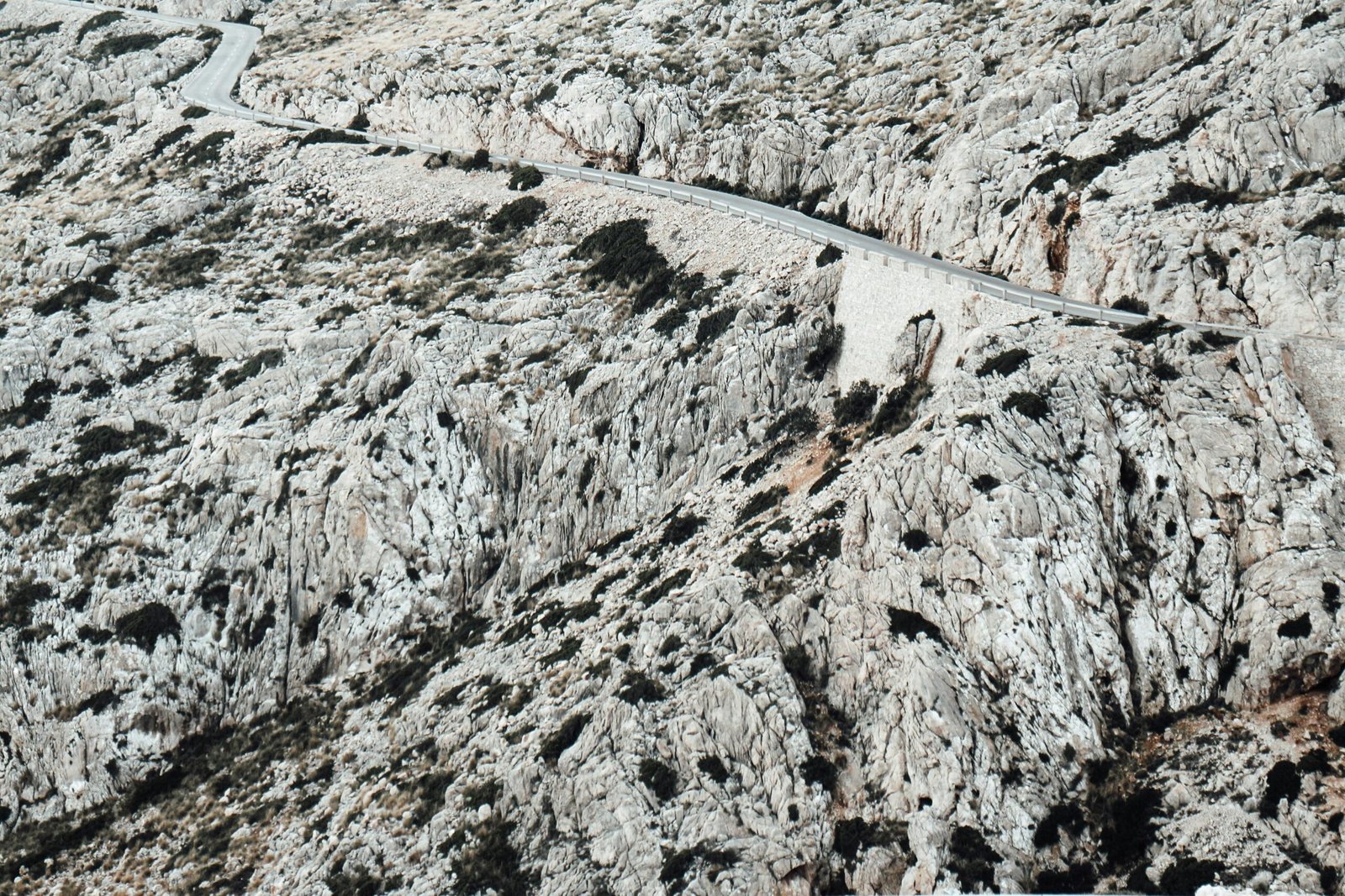 Luftaufnahme einer Straße auf Mallorca, die durch eine bergige Landschaft führt, aufgenommen bei Tageslicht von Barbara Kosulin