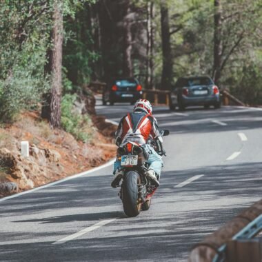 Motorradfahrer in rotem und weißem Anzug fährt auf Mallorca auf einer Straße während des Tages