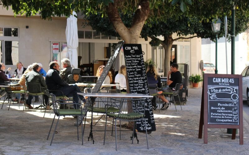 Mann in schwarzer Jacke sitzt auf Mallorca auf einem Stuhl, entspannt im Freien
