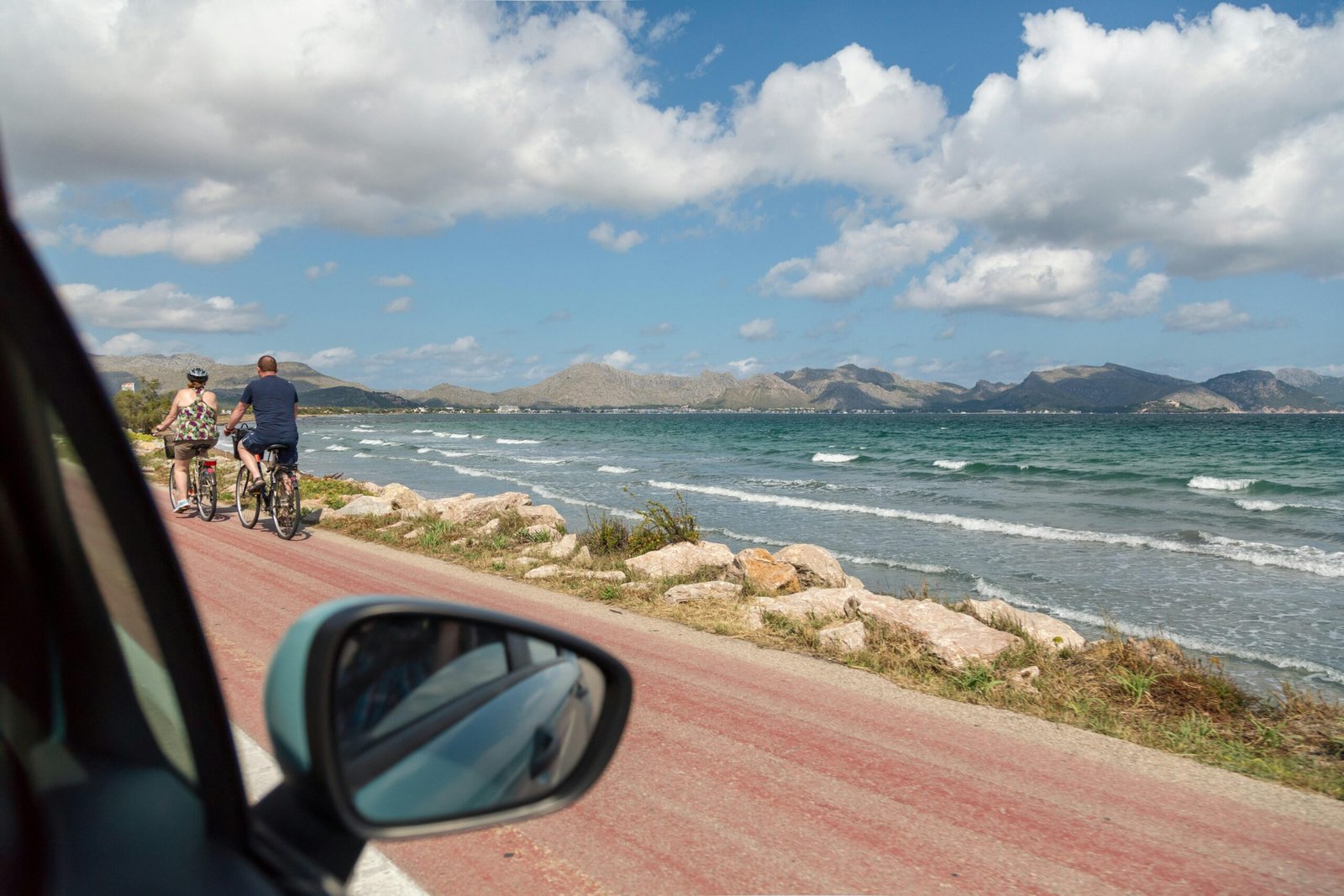 Mann in schwarzer Jacke und blauer Jeans steht am Meeresufer auf Mallorca bei Tageslicht