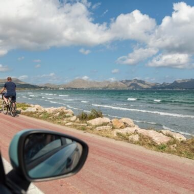 Mann in schwarzer Jacke und blauen Jeans steht am Meeresufer auf Mallorca bei Tageslicht