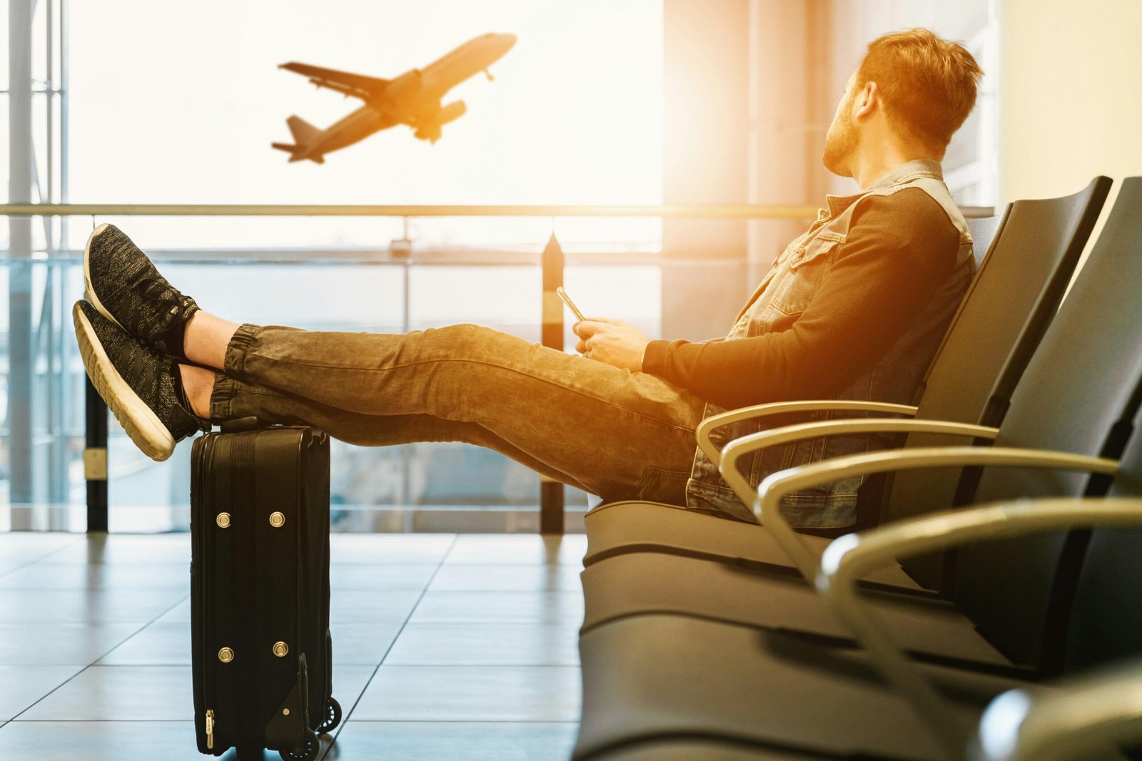 Mann sitzt auf Mallorca auf einem Gangstuhl mit Gepäck und schaut auf ein Flugzeug