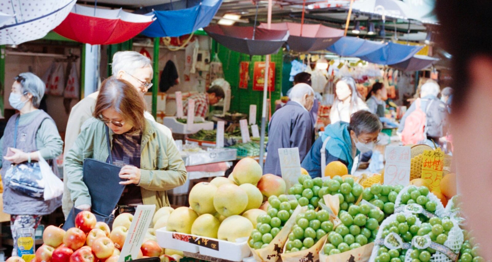 Menschen beim Einkauf auf einem bunten Obstmarkt auf Mallorca, mit frischen Früchten und lebhafter Atmosphäre